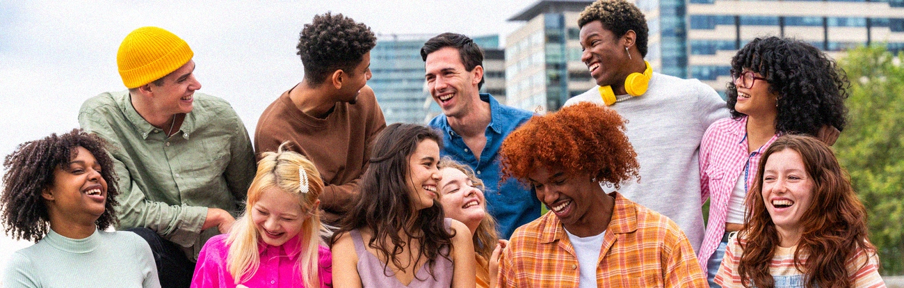 A diverse group of people, including men and women of different races, laughing together.